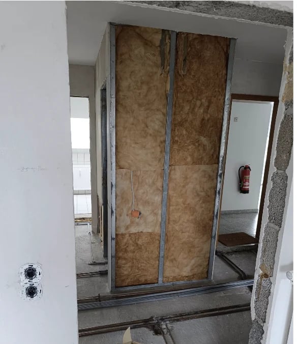Unfinished doorway with plywood sheets covering frame opening in drywall construction interior.
