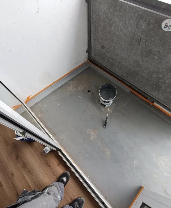 Interior view of an open washing machine or dryer showing an empty drum with a chrome outlet pipe and orange edge trim.